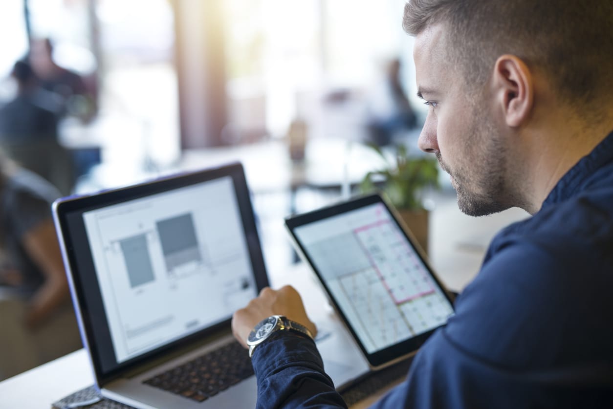 Choosing CMS vendors - Businessman accessing a CMS platform using a laptop and tablet device.