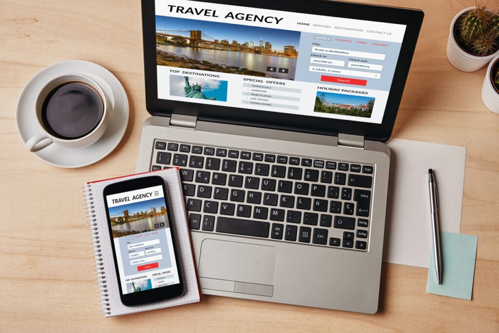 Flat-lay shot of a laptop and mobile phone showing interactive web design on a table with pen, notebook, and cup of coffee