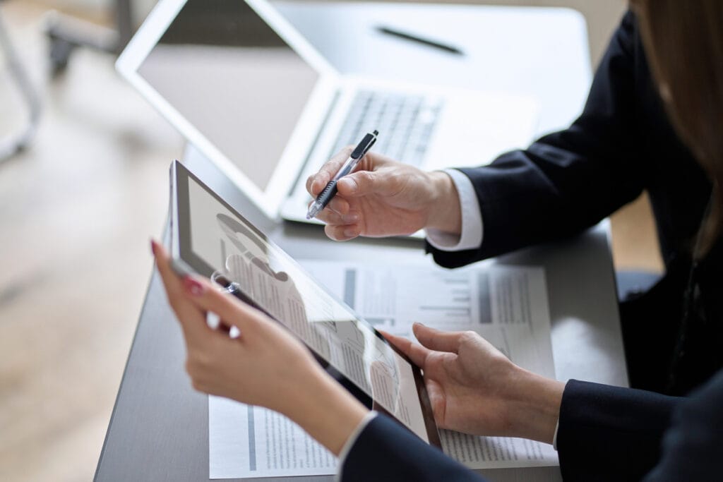 A cropped shot of two people collaborating on a media platform project using a digital tablet and laptop