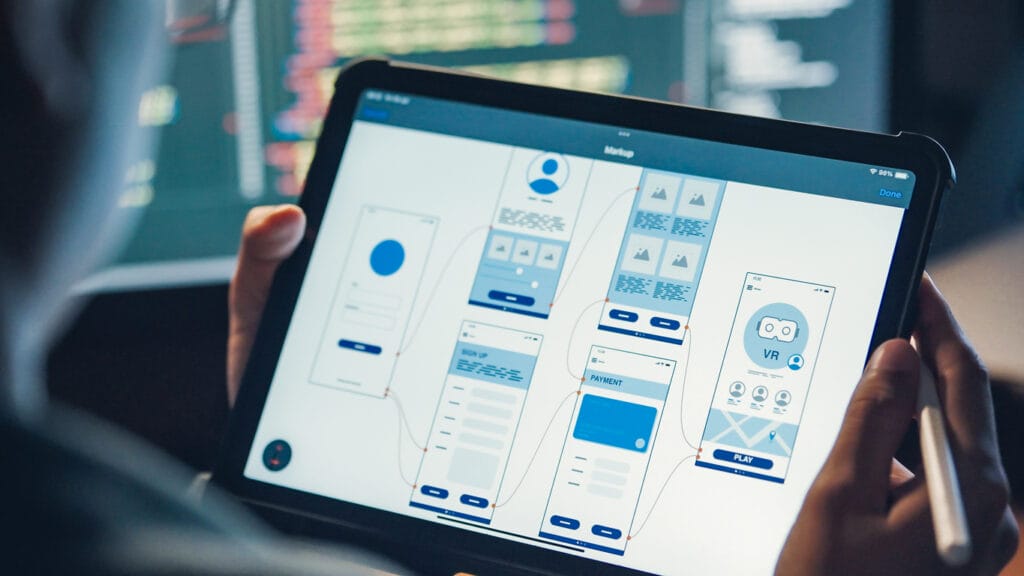 An IT specialist holding a digital tablet examining UI/UX design for a media platform