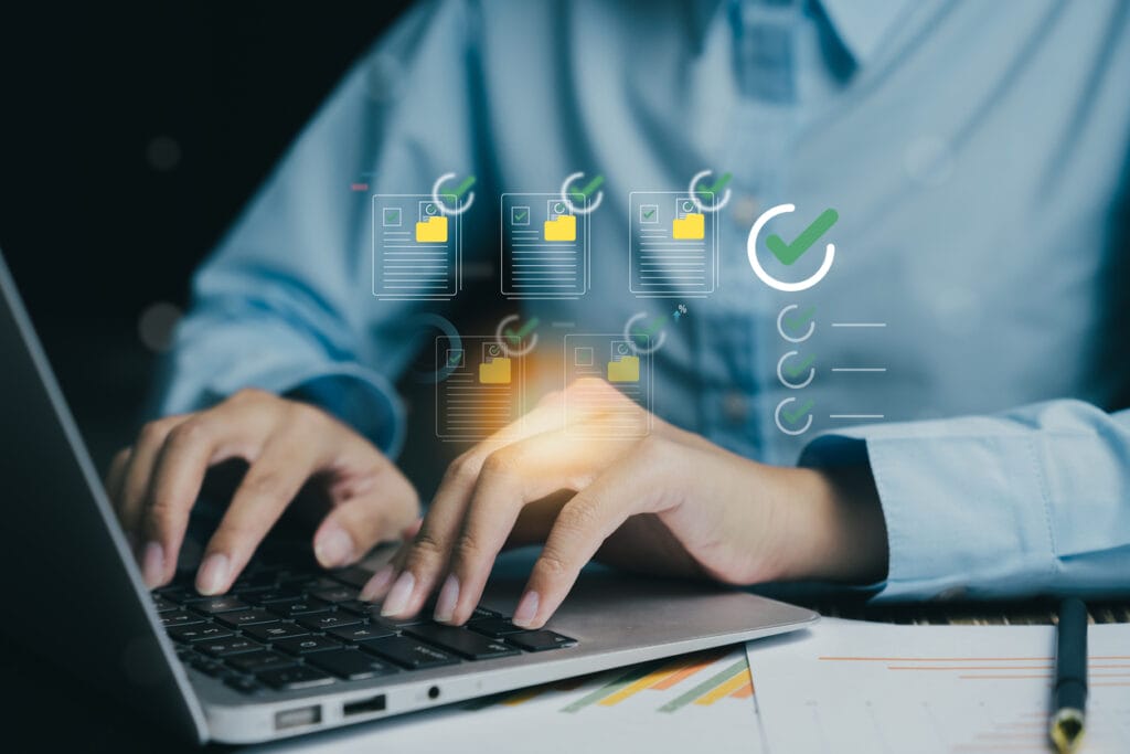A person working on a laptop and overlay of documents with check marks to show accomplished editorial workflow