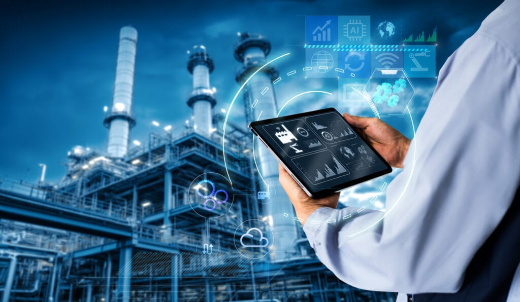 Web platforms for manufacturers: Hands holding a digital tablet with a blurred manufacturing plant in the background
